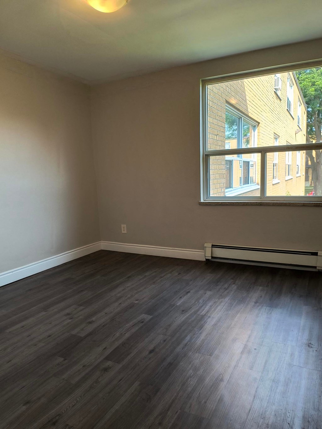 A room with a window and a radiator on the floor.