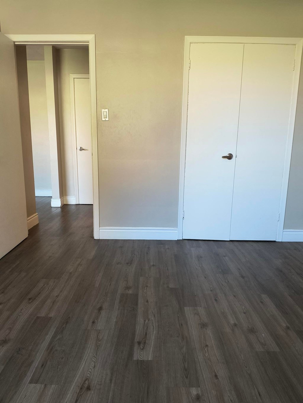 A room with a white door and a grey floor.