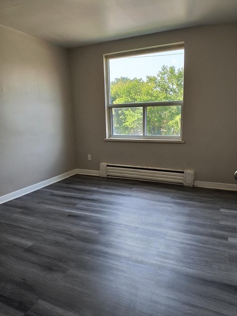 A room with a window and a radiator on the floor.