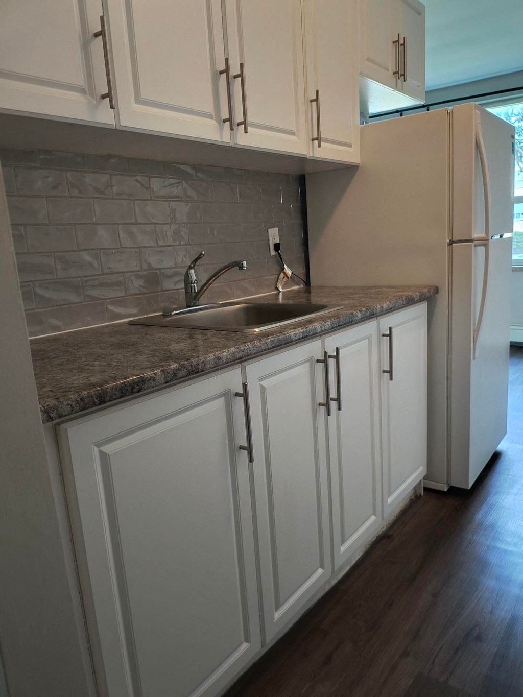 A kitchen with white cabinets and a white refrigerator.