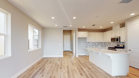 A kitchen with a white counter and wooden floors.