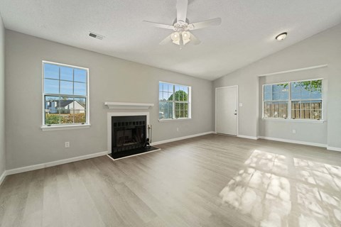 A spacious living room with a fireplace and a ceiling fan.