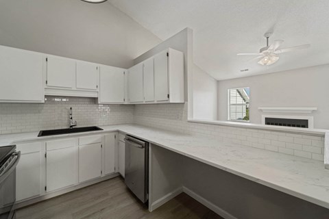 A kitchen with white cabinets and a black fridge.