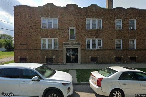 Two white cars parked in front of a brick building.