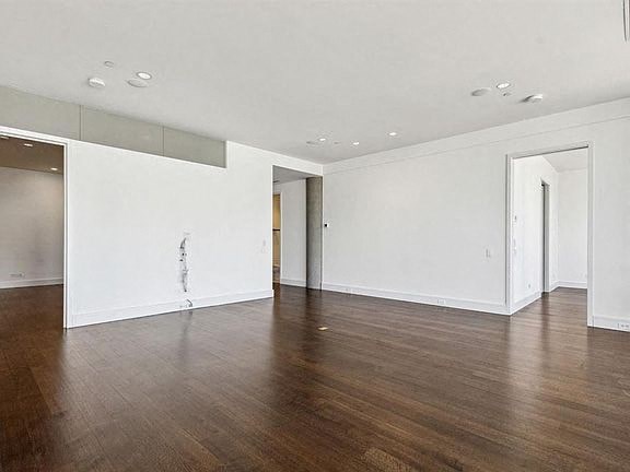 an empty living room with wood floors and white walls
