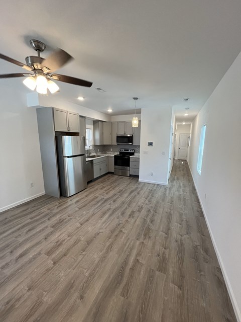 a living room and kitchen with wood flooring and a ceiling fan