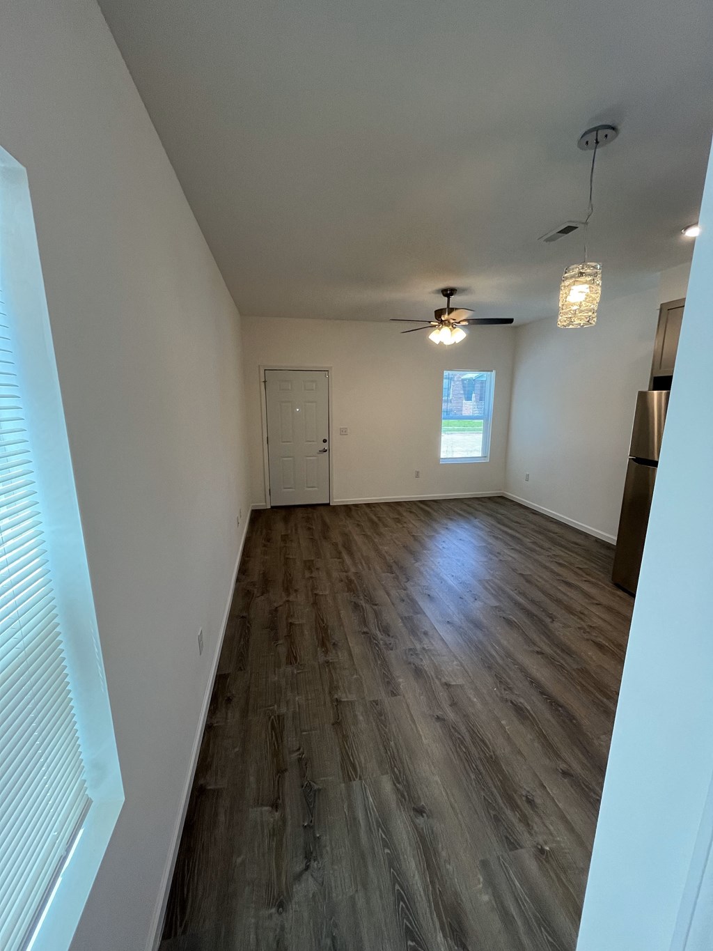 an empty living room with wood floors and white walls