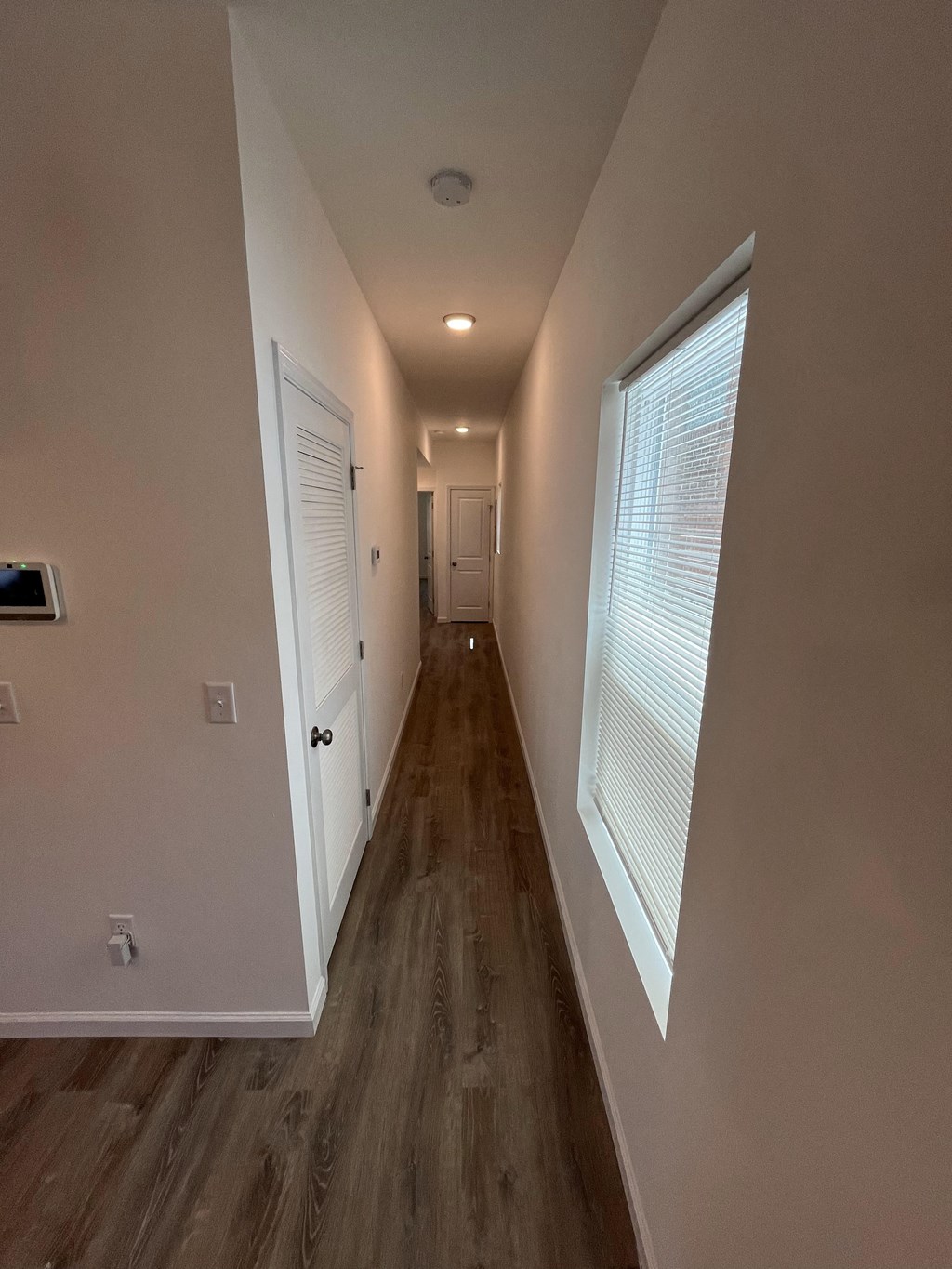 a hallway with wood floors and a large window and a door