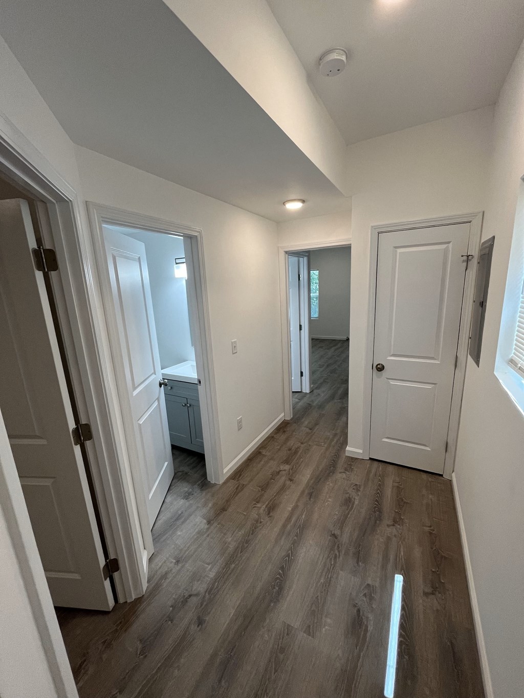 a look down the hallway of a new home with white walls and wood floors