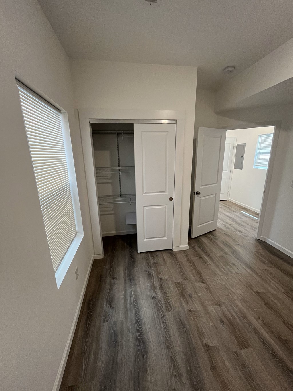 a bedroom with a closet and a hallway with wood flooring