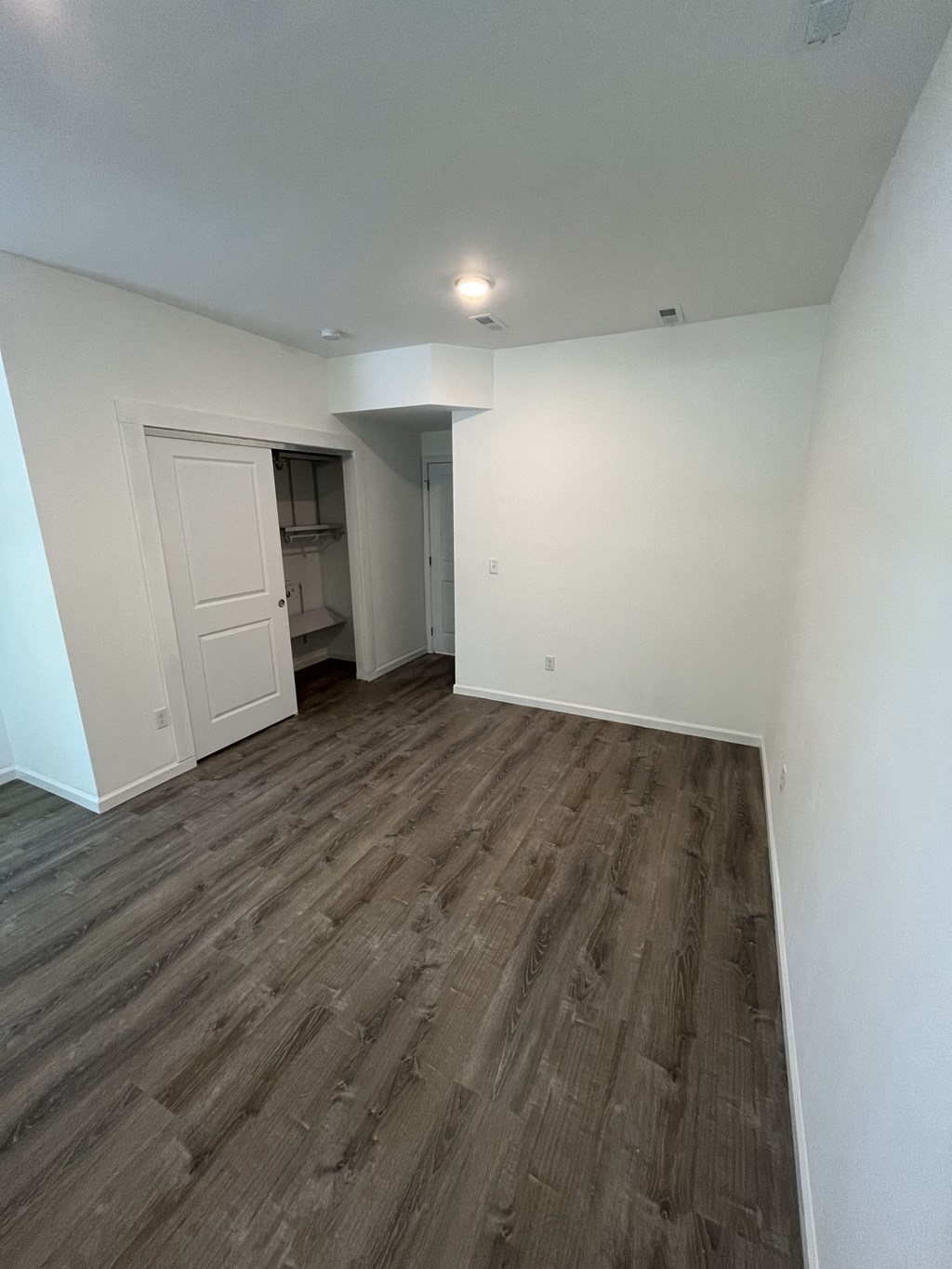 an empty living room with wood flooring and white walls