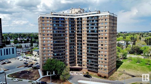 A large, multi-story building with a parking lot in front.
