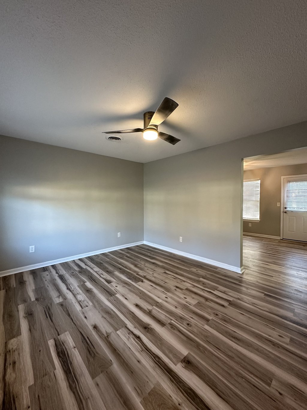 an empty living room with wood floors and a ceiling fan
