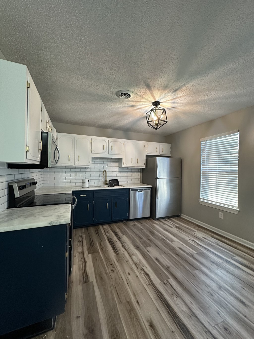 an empty kitchen with wood floors and white cabinets