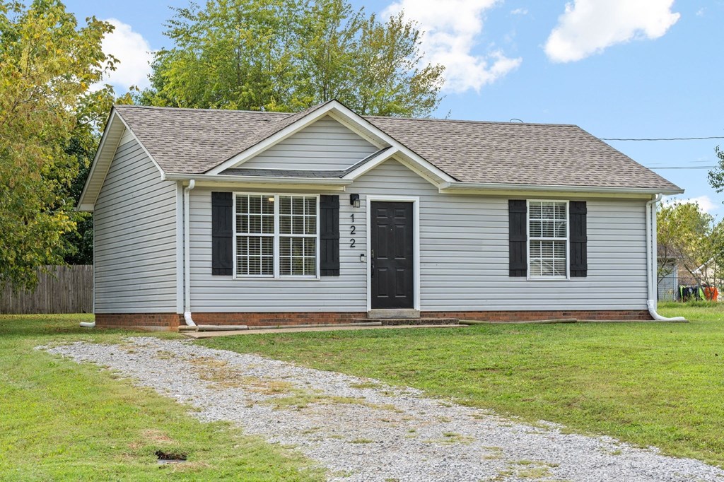 a white house with black shutters and a gravel driveway