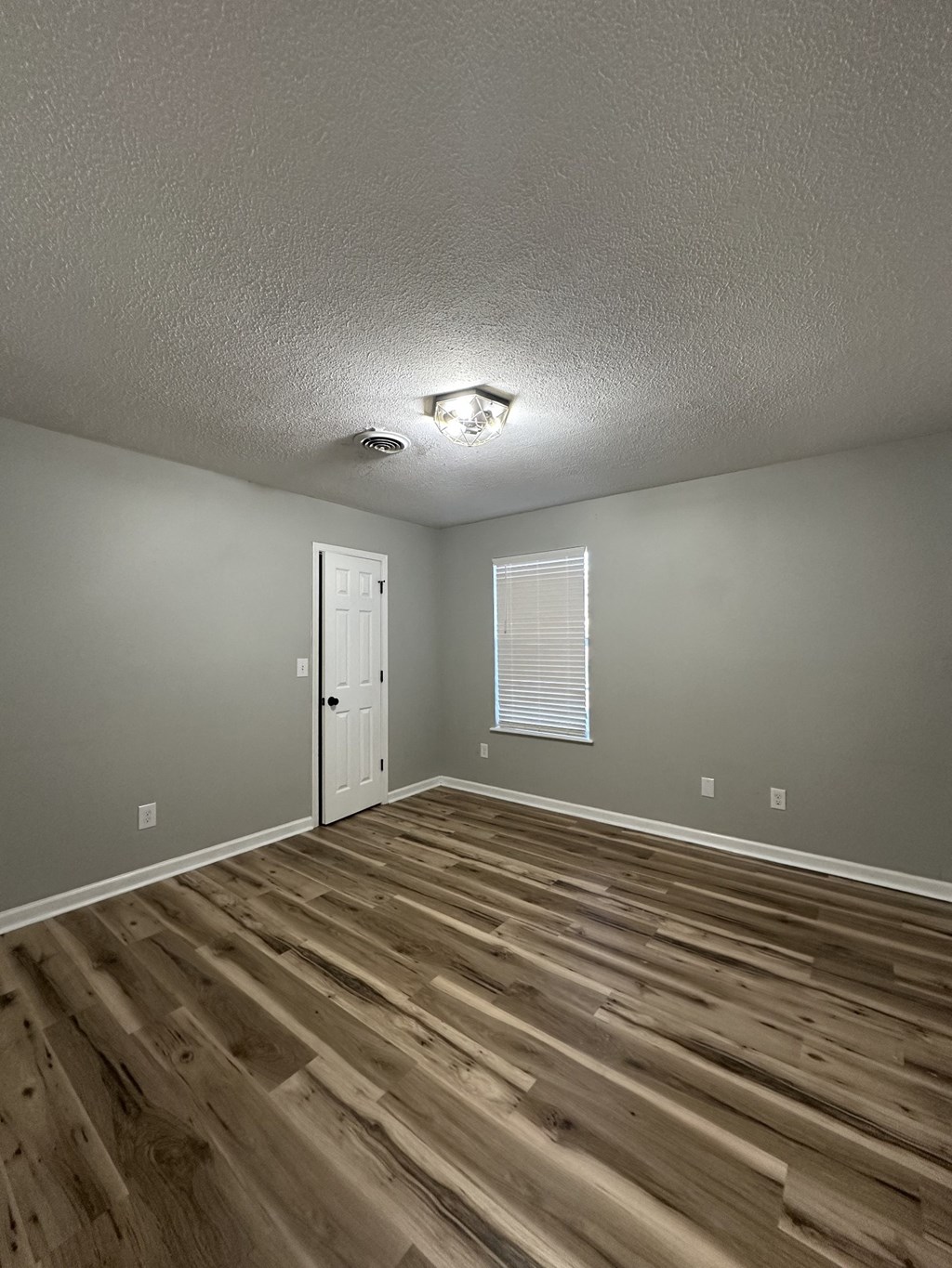 the living room of a rental house with wood floors and a white door