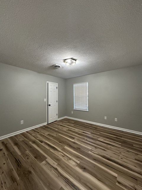 the living room of a rental house with wood floors and a white door
