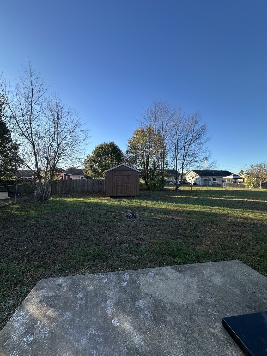a backyard with a wooden fence and a shed in the grass