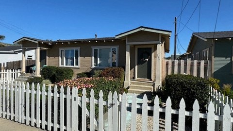 a small house with a white fence in front of it