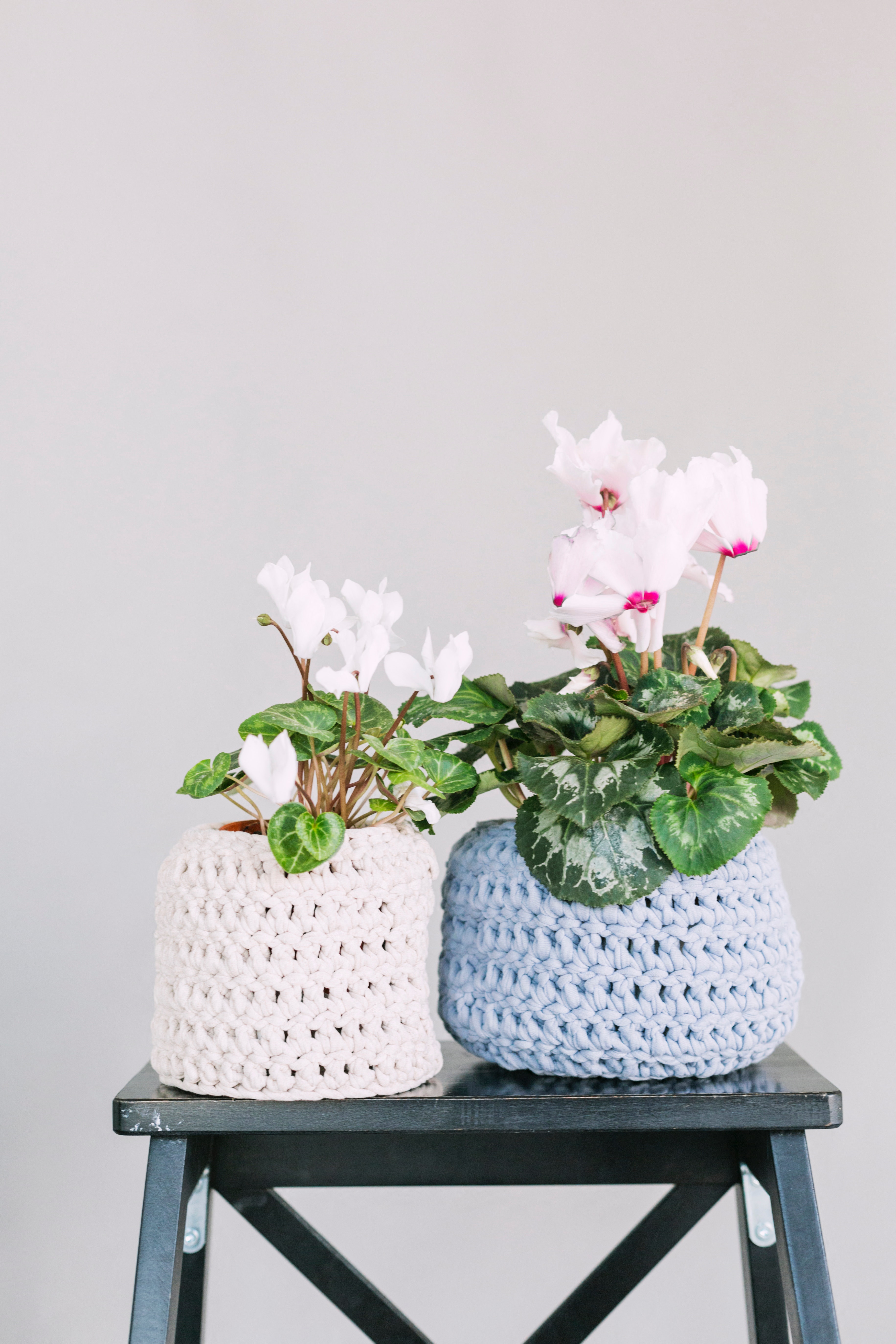a pair of crochet vases with flowers on a table