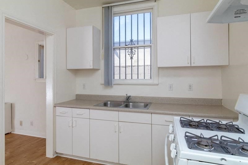 A kitchen with white cabinets and a stove top oven.