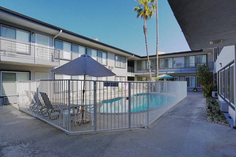 A pool area with a blue umbrella and chairs.