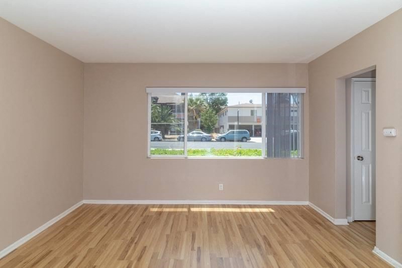 A room with wooden floors and a window showing a street view.