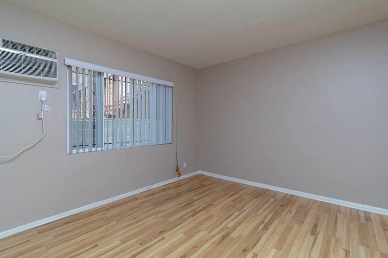 A room with wooden flooring and a window with blinds.