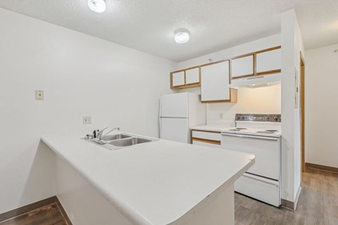 A kitchen with white appliances and a white counter.