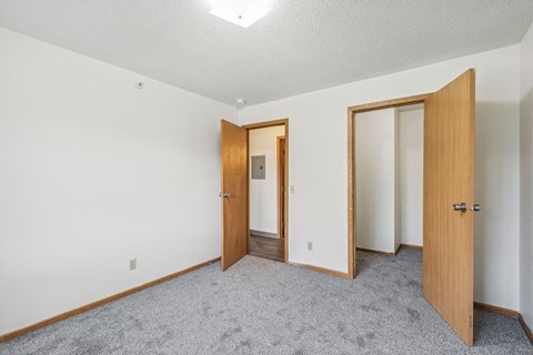 A room with three doors and carpeted floor.