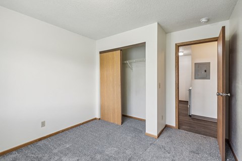 A room with a carpeted floor and two open doors.