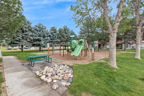 A playground with a green slide and a green bench.