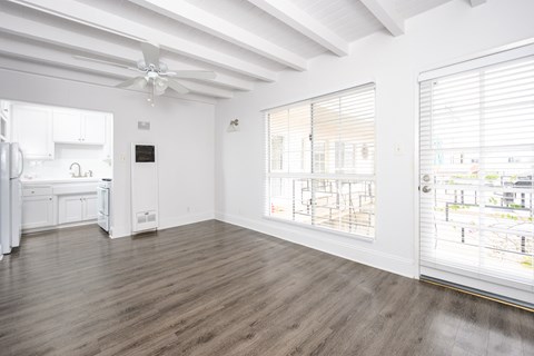 an empty living room with a large window and a kitchen