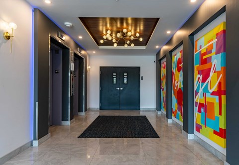 A hallway with a black door and a chandelier.