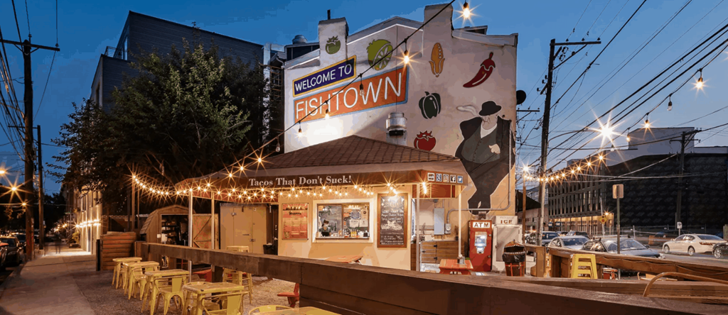 the exterior of a restaurant at night with lights on the building