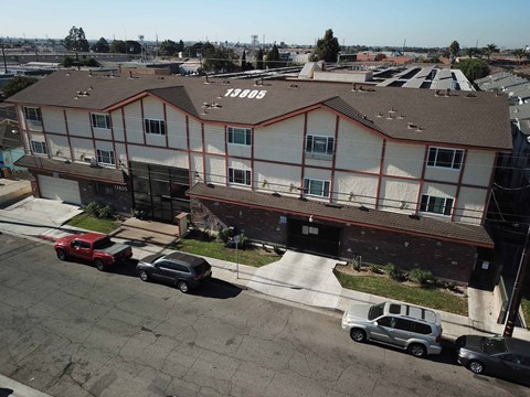 A red car is parked in front of a white and brown building.
