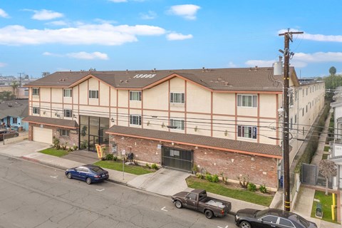 A blue car is parked in front of a brown building.