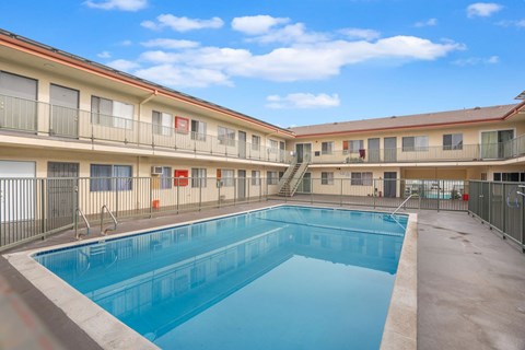 A swimming pool is located in the middle of a courtyard surrounded by apartment buildings.