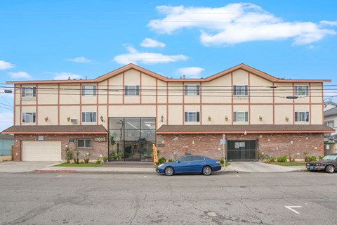 A blue car is parked in front of a building with the number 1805 on it.