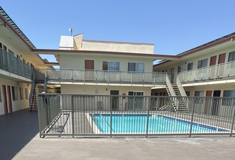 A pool is surrounded by a fence in a courtyard.