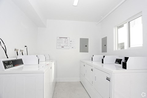 A white laundry room with washers and dryers.
