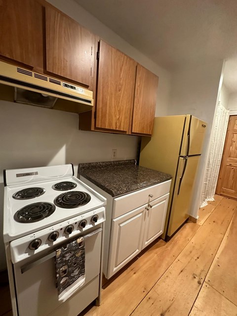 A kitchen with a white stove and a yellow refrigerator.
