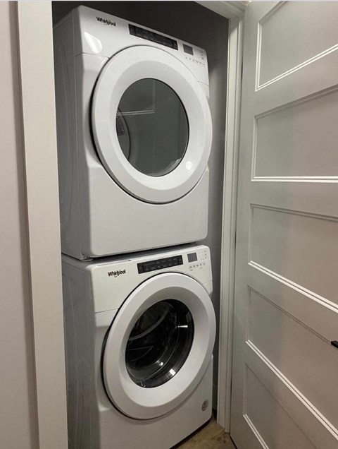 Two white Whirlpool washing machines stacked on top of each other.