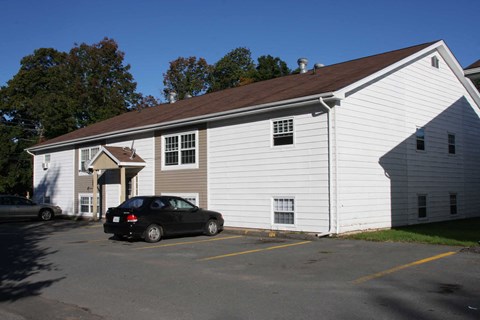 A white building with a black car parked in front.