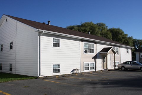 A white building with a car parked in front.