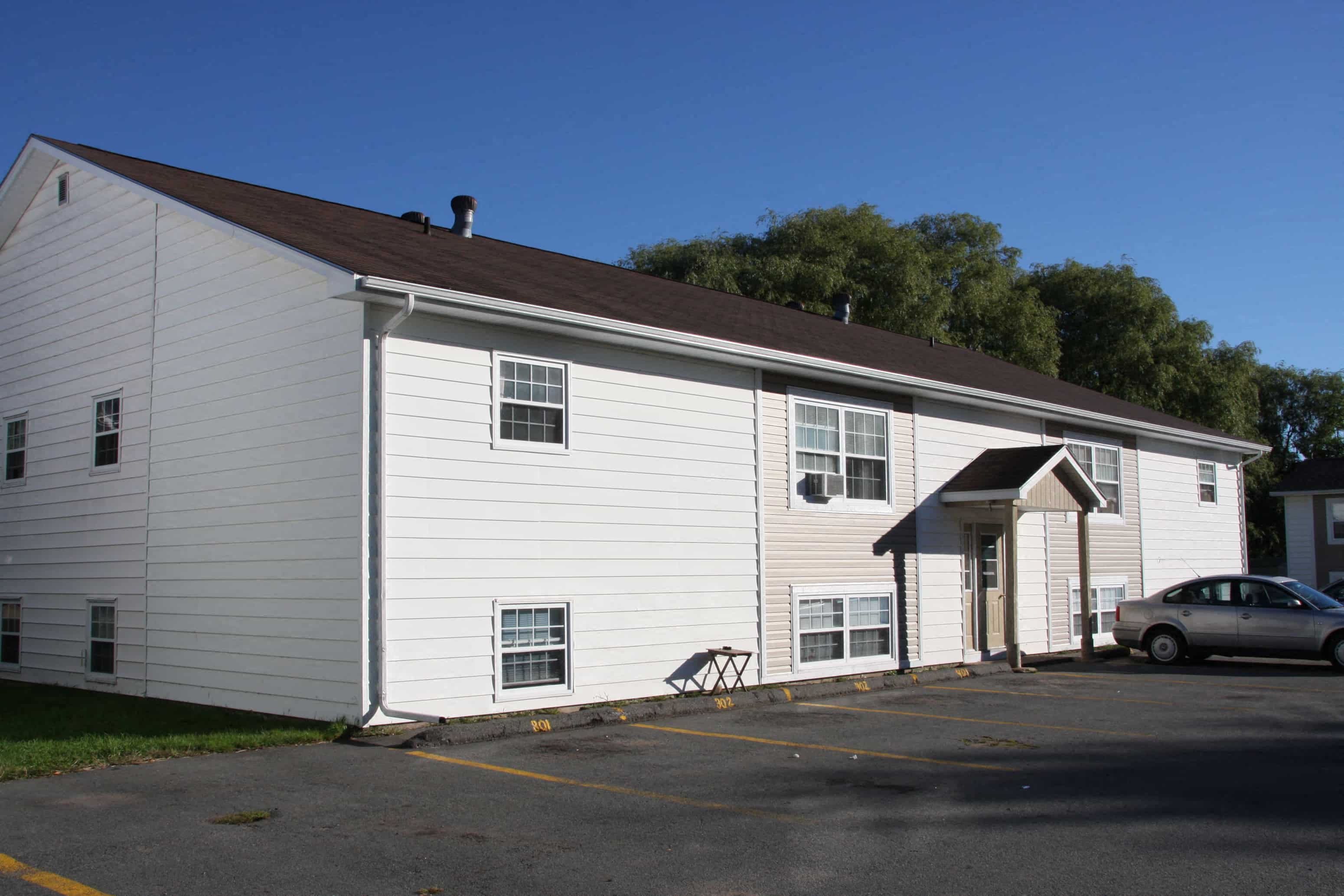 A white building with a car parked in front.