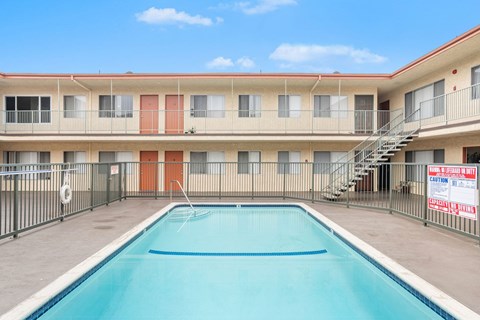 A swimming pool in front of a multi-story apartment building.