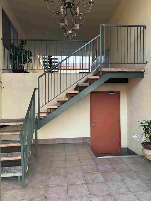 A staircase with a metal railing and a red door.