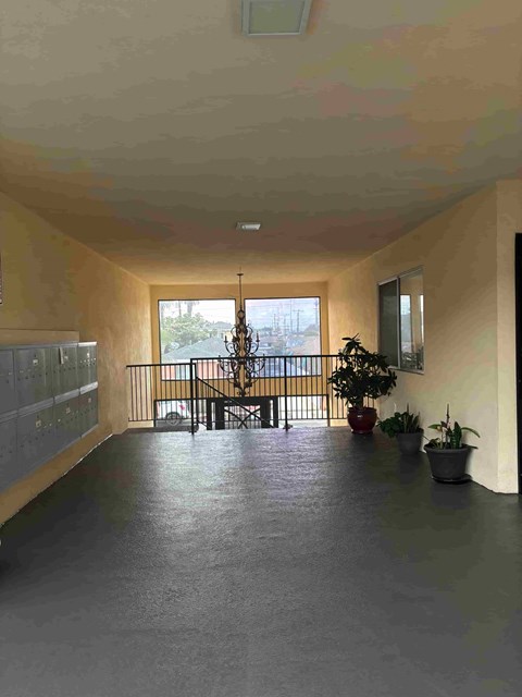 A long hallway with a balcony and potted plants.