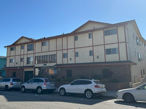 A building with a red and white facade has cars parked in front of it.